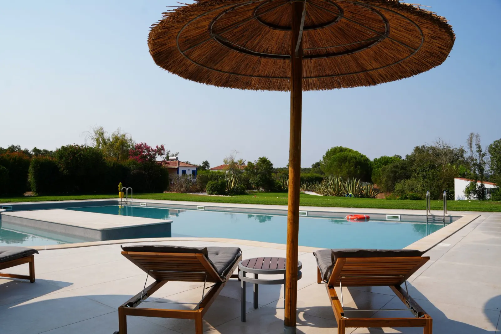 Loungers under a thatched parasol by the saltwater pool
