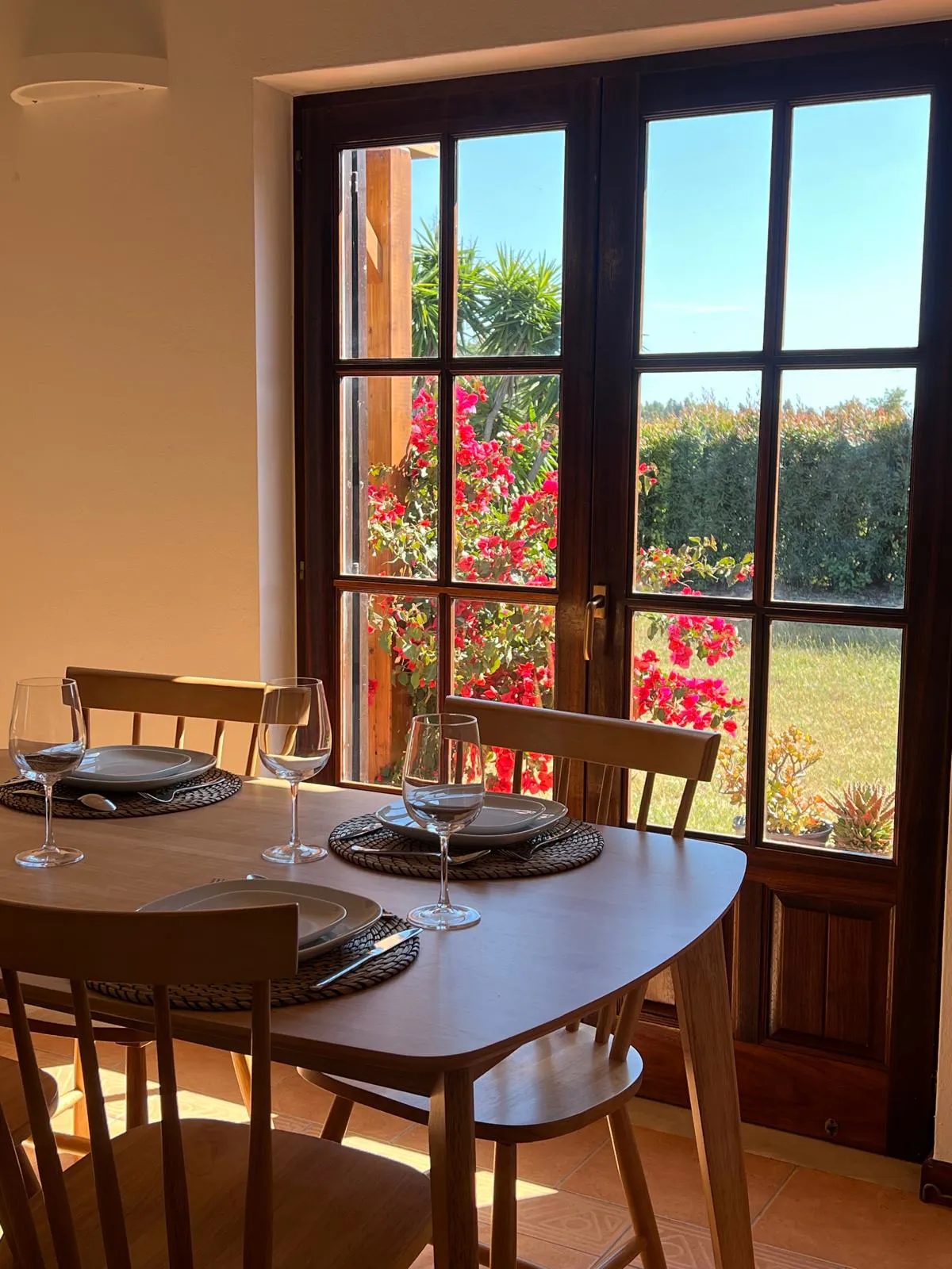 A table laid by the window, bougainvillea outside